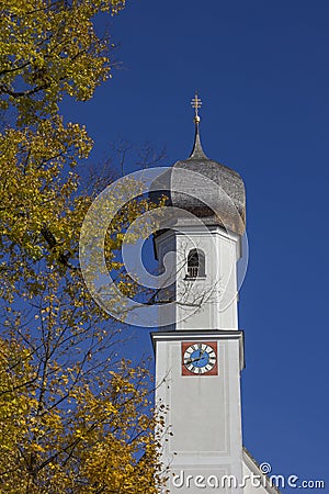 village church in gmund, golden beech leaves and blue sky, bavaria Stock Photo