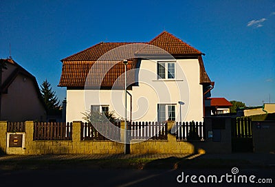 Village house with white facade and red rood seen from the street against deep blue sky in the background Editorial Stock Photo