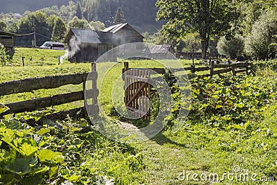 Village landscape, houses, fence and open gate Stock Photo