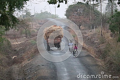 Village road in rural area with tractor carrying hay or dried grass Editorial Stock Photo