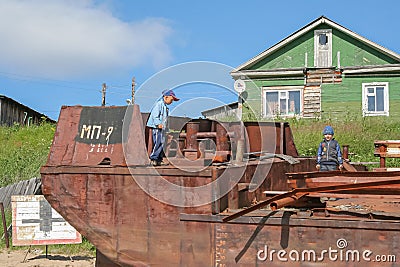 A village in Russia in the summer, children play on old rusty ships. The village of Ust-Tsilma, the original authentic life of the Editorial Stock Photo