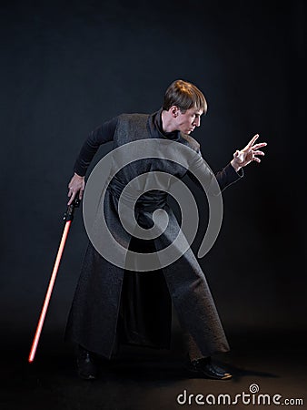 A villain with a red lightsaber, a young man in a long robe does fighting poses, Stock Photo