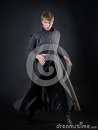 A villain with a red lightsaber, a young man in a long robe does fighting poses, Stock Photo