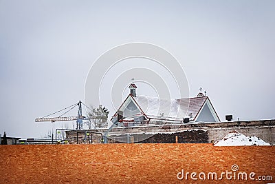 Vilnius, Lithuania - 04122021: The construction site on the old block behind a plywood fence with church roof visible over it Editorial Stock Photo