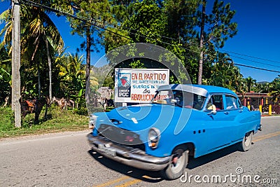 VINALES, CUBA - FEB 18, 2016: Vintage car and a propaganda poster near Vinales village, Cuba. It says: The dreams of all Editorial Stock Photo