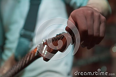 Vinnytsia, Ukraine - 02.14.2014: guitarist`s hand tuning pegheads of his electric solo guitar on stage during rock concert Editorial Stock Photo