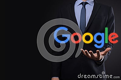 VINOGRADIV, UKRAINE - 30 DECEMBER 2020. Businessman in a suit on a dark background holds a Google logo inscription. Google is Editorial Stock Photo