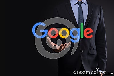 VINOGRADIV, UKRAINE - 30 DECEMBER 2020. Businessman in a suit on a dark background holds a Google logo inscription. Google is Editorial Stock Photo
