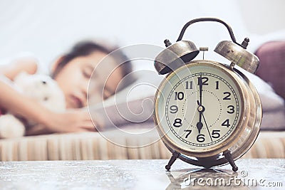 Vintage alarm clock on cute asian child girl sleeping in the bed Stock Photo