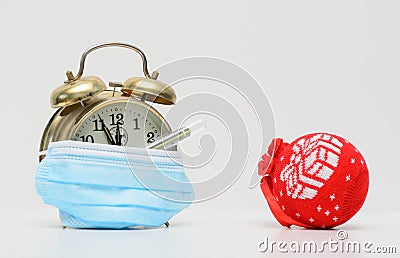 Vintage alarm clock partially covered by a medical mask Stock Photo