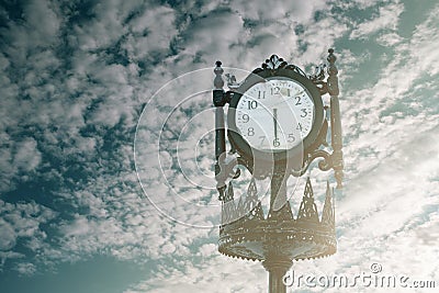 Vintage analogue clock against sunset with beautiful clouds. Stock Photo