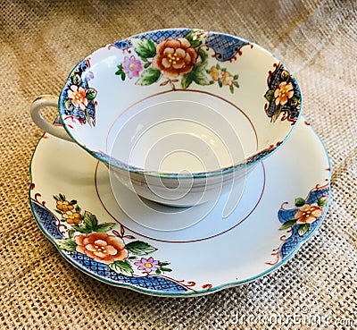 Vintage Antique Fine Bone China with Gold Trim and Flowers Teacup and Saucer on Burlap Background Stock Photo