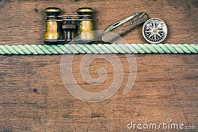 Vintage binoculars, compass, old pocket knife, rope on wooden grunge desk background Stock Photo