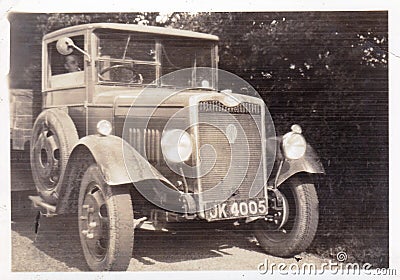 Vintage black and white photo of a old truck with man smoking at wheel 1920s? Editorial Stock Photo