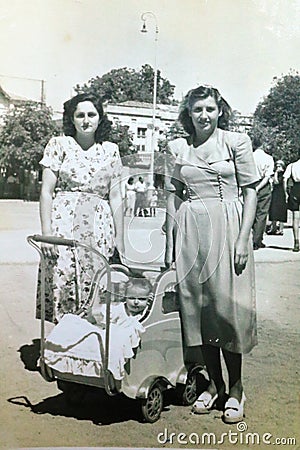Vintage black and white photo of sisters with a child in pram, family, 1950s European. Editorial Stock Photo