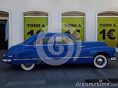 Vintage blue car parked in front of signs with the text in Spanish `todo a 1 euro` everything at 1 euro Editorial Stock Photo