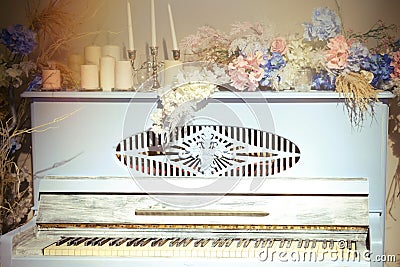 Vintage blue piano, close-up. Retro musical instrument with red flowers and candles Stock Photo