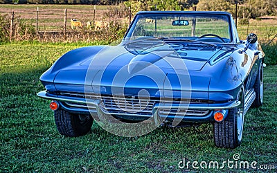Vintage blue sports car convertible by a pasture at sundown. Stock Photo