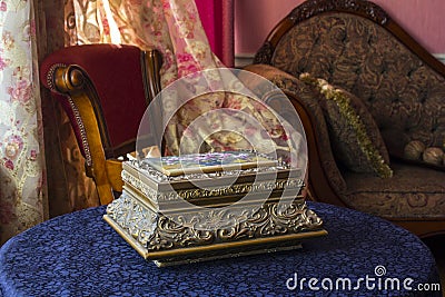 Vintage box. Antique casket on the table against the background of a classic interior consisting of a chair curtains and couch Stock Photo