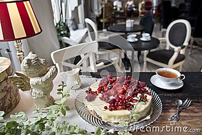 Vintage cafe, on the old steel cake with berries, a cup of tea, a milk jug and a bear with wings Stock Photo