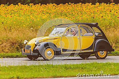 Vintage Citroen 2CV in front of a field with blooming sunflowers Editorial Stock Photo