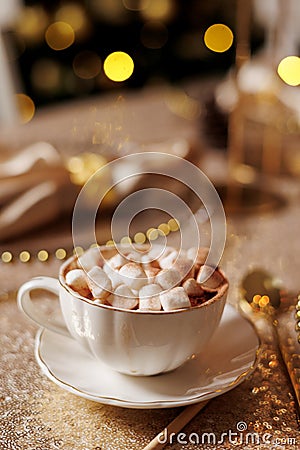 Vintage classic white porzellan cup with saucer with cacao and marshmallow on golden glittering tablecloth. Christmas or Stock Photo
