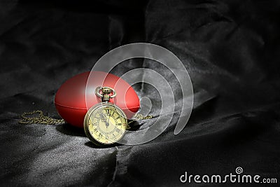Vintage clock and red heart on black background ,Love and time concept in still life photography. Stock Photo