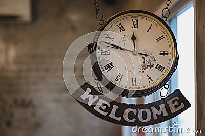 Vintage clock with roman number and welcome label hanging Stock Photo