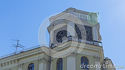 The vintage clock tower on facade of the residential building on blue sky background with sun glare. Urban backgrouund Stock Photo