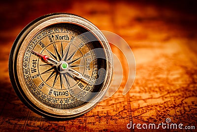 Vintage compass lies on an ancient world map. Stock Photo