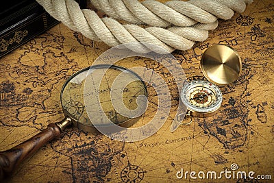 Vintage Compass and magnifying glass lies on an ancient world map - adventure stories background Stock Photo