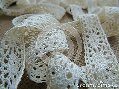 Vintage cotton cream lace on burlap background. Stock Photo