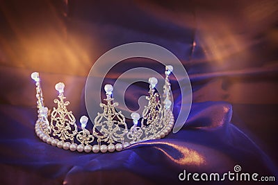 Vintage crown over dark royal purple delicate silk. fantasy medieval period Stock Photo