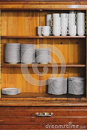 Vintage cupboard with dinnerware. old wooden kitchen cabinet with stack of white plates and cups. retro sideboard Stock Photo