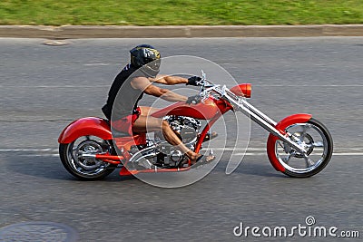 Vintage customized motorcycle riding down the street. Restored motorcycle in orange color. Riga, Latvia - August 15, 2022 Editorial Stock Photo