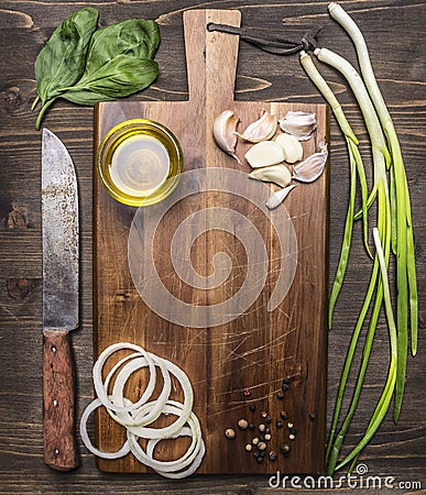 Vintage cutting board with ingredients for cooking, garlic, onion rings, green onions Oil knife place for text,frame on wooden Stock Photo