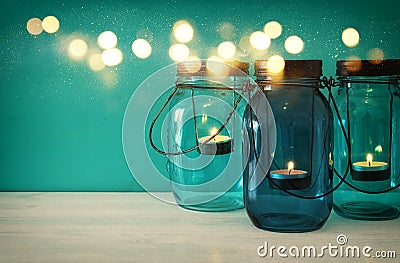 vintage decorative magical mason jars with candle light on wooden table Stock Photo