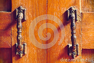 The vintage door handle on an old wooden door background and lighting and shadow in the morning. Stock Photo