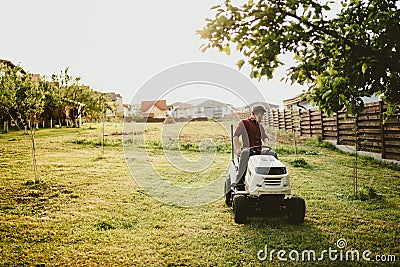 Vintage effect of landscaping works. Male worker riding a tractor grass trimmer Stock Photo