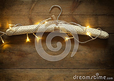 Vintage fabric hanger with gold Christmas warm gold garland lights on wooden rustic background. filtered image Stock Photo