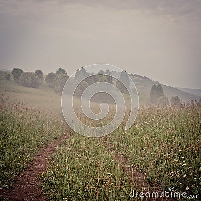 Vintage faded image of a country mountain road in misty morning before sunrise Stock Photo