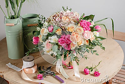 Vintage floristic background, colorful roses, antique scissors and a rope on an old wooden table Stock Photo