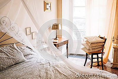 Vintage furniture retro sunny apartment with Baldachin bed, chair, cozy pillows, lamp, framed pictures on the walls Stock Photo