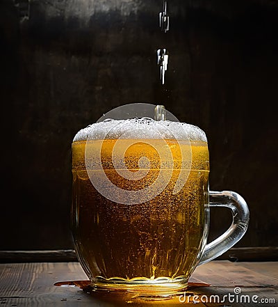 Vintage glass of beer with foam on a wooden board against a dark background Stock Photo