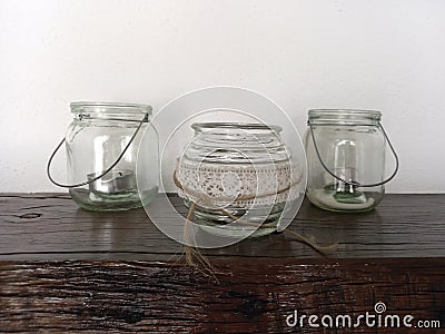 Vintage glass jars used as candle holders on rustic wooden table. Hanging clear glass candle holder. Retro decor. Home and Stock Photo