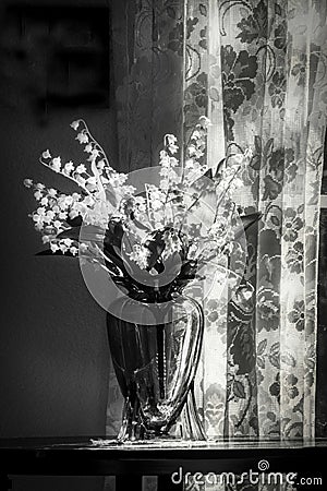 A Mood Drenched Photo of Lace and Lilys of the Valley in a Vase Stock Photo