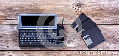 Vintage handheld computer and data disks on rustic wooden boards Stock Photo