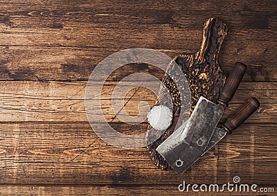 Vintage hatchets for meat on wooden chopping board with salt and pepper on wooden table background. Space for text Stock Photo