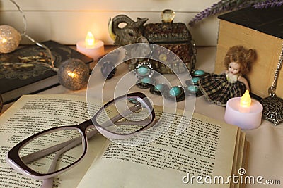 Vintage horizontal still life: printed book, candle glasses, vintage jewelry, small faience doll Stock Photo