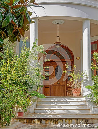 A vintage house entrance stairs with natural wooden arched double doors and potted plants Stock Photo